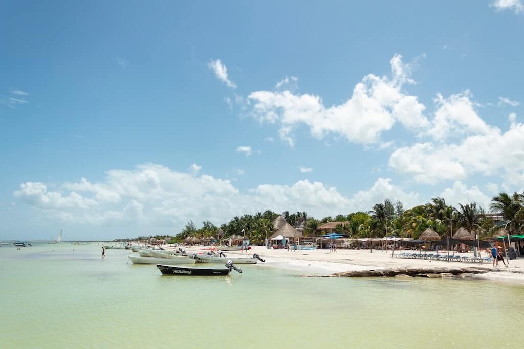looking from the water toward the beaches of Isla Holbox with boats in the foreground and palm trees in the background.